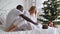 Young happy multi-ethnic family of mother, father and little daughter dressed in white at background of Christmas and