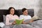 Young happy pair reading books while lying in the bed and wearing pajama