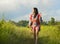 Young happy and playful Asian Chinese woman in beautiful dress having fun enjoying holidays excursion on grass tropical field smil