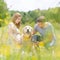 Young happy pregnant couple petting it`s Golden retriever dog outdoors in meadow.