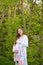 Young happy pregnant woman walking in forest and wearing dress.