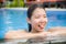 young happy and pretty Chinese Asian woman enjoying cheerful and relaxed having fun smiling at swimming pool of resort hotel in Su