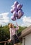 Young happy pretty girl 17-18 years old with a bunch of purple helium balloons