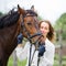 Young happy rider woman with her bay horse