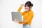 Young happy smiling Asian woman in yellow casual clothes holding laptop