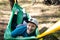 Young happy smiling man in hat relaxing outside in hammock in forest.