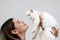 Young happy smiling woman holding cute white Persian cat and lift up her cat, try to kiss her pet, happy beautiful lady playing