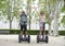 Young happy tourist couple riding segway enjoying city tour in Madrid park in Spain together