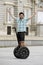 Young happy tourist man wearing safety helmet headgear riding city tour segway driving happy