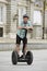 Young happy tourist man wearing safety helmet headgear riding city tour segway driving happy