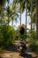 Young happy tourist woman with hat riding scooter motorbike in tropical paradise jungle with blue sky and palm trees exploring tr