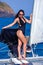 Young happy woman in black dress enjoying evening sun at yacht