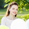 Young happy woman with bunch of balloons in park