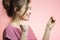 Young happy woman with checking result of a one-time pregnancy test, family planning, motherhood concept on pink studio background