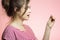 Young happy woman with checking result of a one-time pregnancy test, family planning, motherhood concept on pink studio background