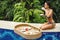 Young happy woman with a floating breakfast in the pool