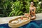 Young happy woman with a floating breakfast in the pool