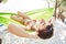 Young happy woman in a hammock on the beach