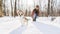 Young happy woman having fun in snowy winter park with Corgi baby dog