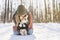 Young happy woman having fun in snowy winter park with Corgi baby dog