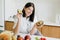 Young happy woman holding halves of ripe avocado and smiling in modern kitchen. Healthy eating