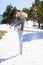 Young happy woman kicking snow in a snow-covered forest in the mountains