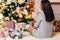 Young happy woman in knitted sweater. delicate Christmas decor, pink decorations on the Christmas tree. woman sitting