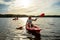 Young Happy Woman Paddling Kayaks on the Beautiful River or Lake under Dramatic Evening Sky at Sunset