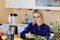 Young happy woman peeling cucumber in kitchen