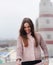 Young happy woman portrait, looking down and smiling, dressed in cute gentle pink sweater, autumn fashion