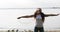 Young happy woman with red curly hair enjoying music in earphones on a shore of lake.