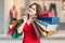 Young happy woman is shopping and holds many bags in hands