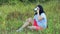 Young happy woman sitting on grass drinking tea and admiring nature.