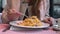 Young happy woman sitting at the table in cafe and enjoying the meal. Hungry woman eating tasty pasta.