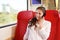 Young happy woman sitting in train talking on smart phone