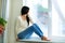 Young happy woman sitting on a window-sill