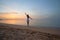 Young happy woman standing on sandy beach by seaside enjoying warm tropical evening