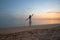 Young happy woman standing on sandy beach by seaside enjoying warm tropical evening