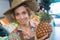 Young happy woman in supermarket holding pineapple