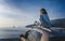 Young happy woman traveler sitting on car roof enjoying sea and sunset view. Summer vacation and adventure