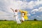 Young happy women jumping and holding silk shawls in meadow