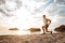 Young healthy man athlete doing squats at the beach