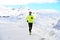 Young healthy sport man running in snow mountains in trail runner hard workout in winter