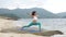 Young healthy sporty woman practicing yoga on the beach at sunset.