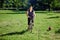 Young healthy woman rides bike in park with small dog running near.