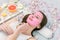 Young healthy woman in spa making treatments and face mask, natural cosmetics and fruits around her. Young woman in a