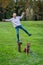 Young at Heart, middle aged woman balancing on an iron standpipe in a grassy park, dog not watching