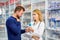 Young helpful female druggist dealing with a male customer, explaining a prescription