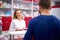 Young helpful female druggist dealing with a male customer, explaining a prescription