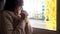 Young helpless woman praying, sitting on window sill, God faith, loneliness